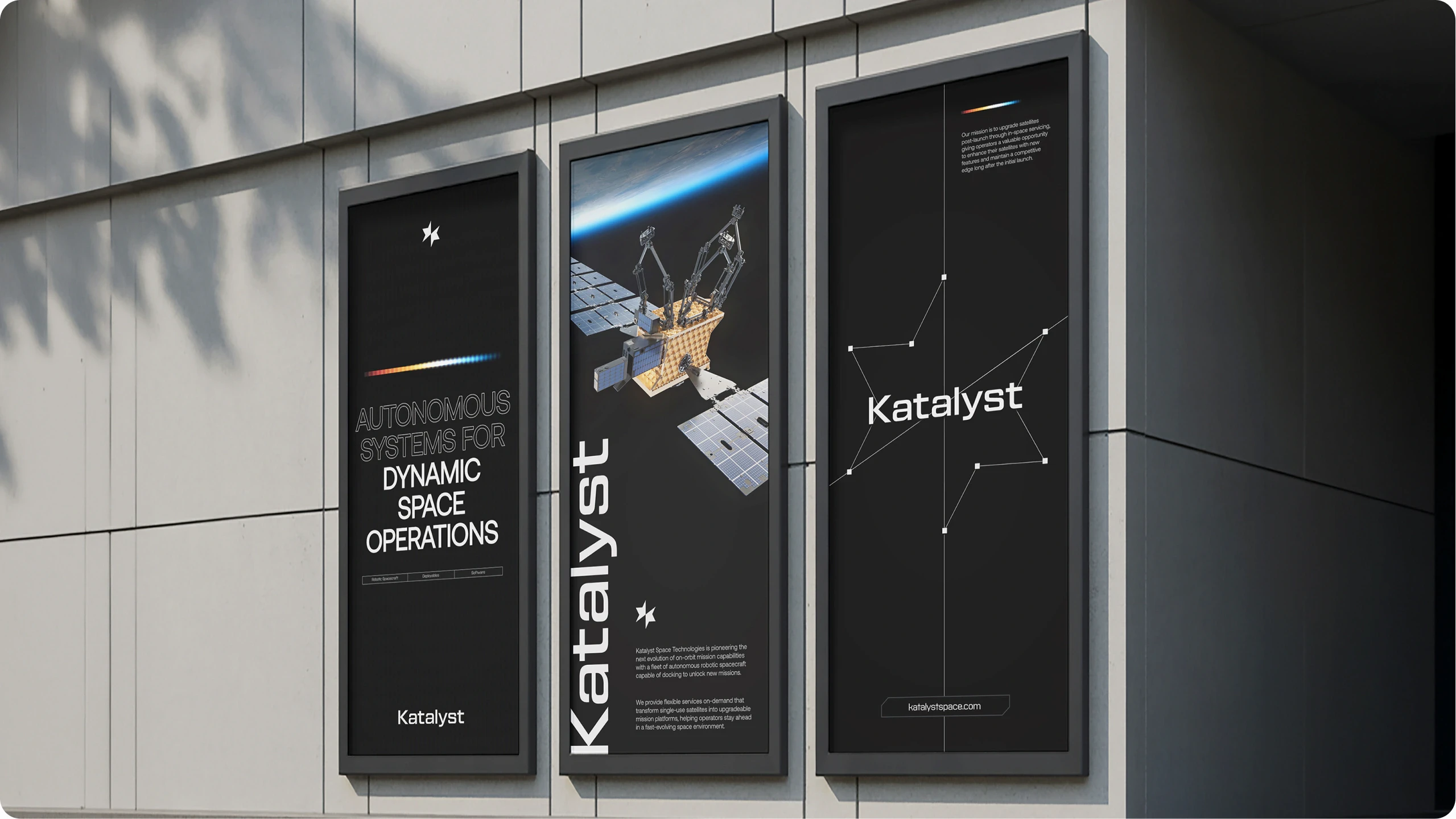 Three vertical digital posters on a building wall showcasing Katalyst's autonomous systems for dynamic space operations with a robotic spacecraft image and constellation lines.