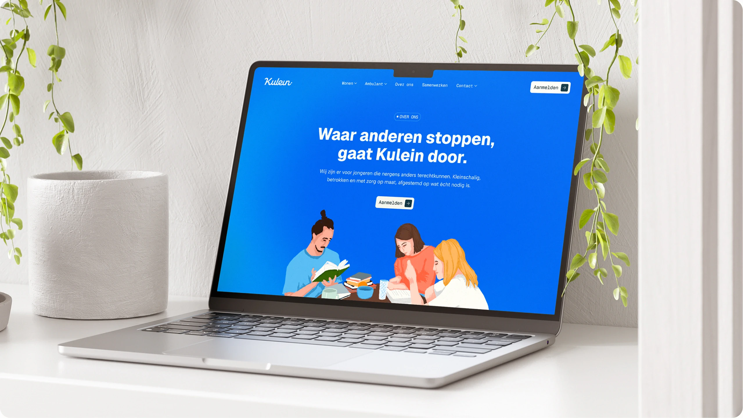 Open laptop on white desk with a blue website homepage showing three people reading books and Dutch text.