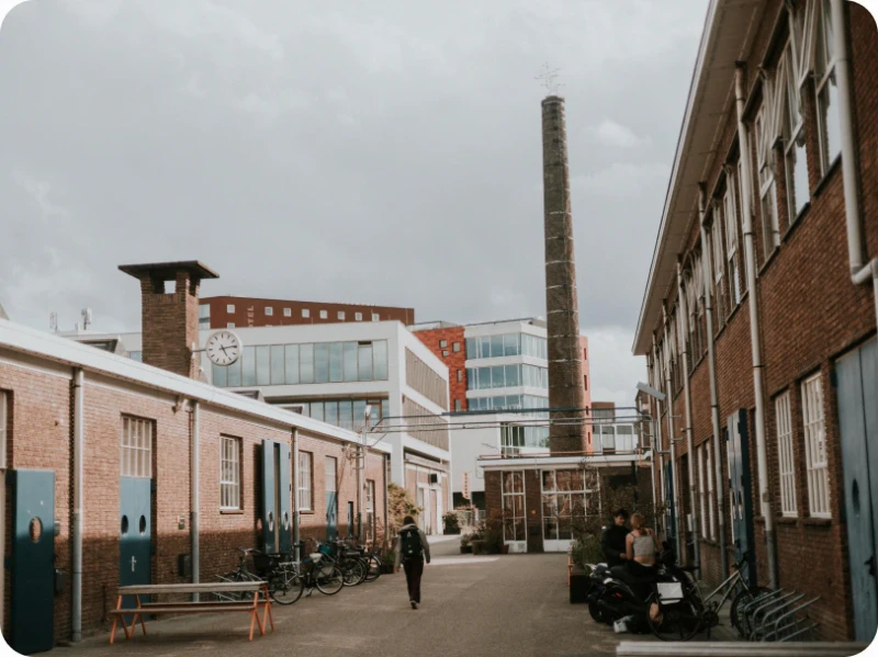 Brick factory buildings along a cobbled street with a tall chimney, where the Perspective office is.