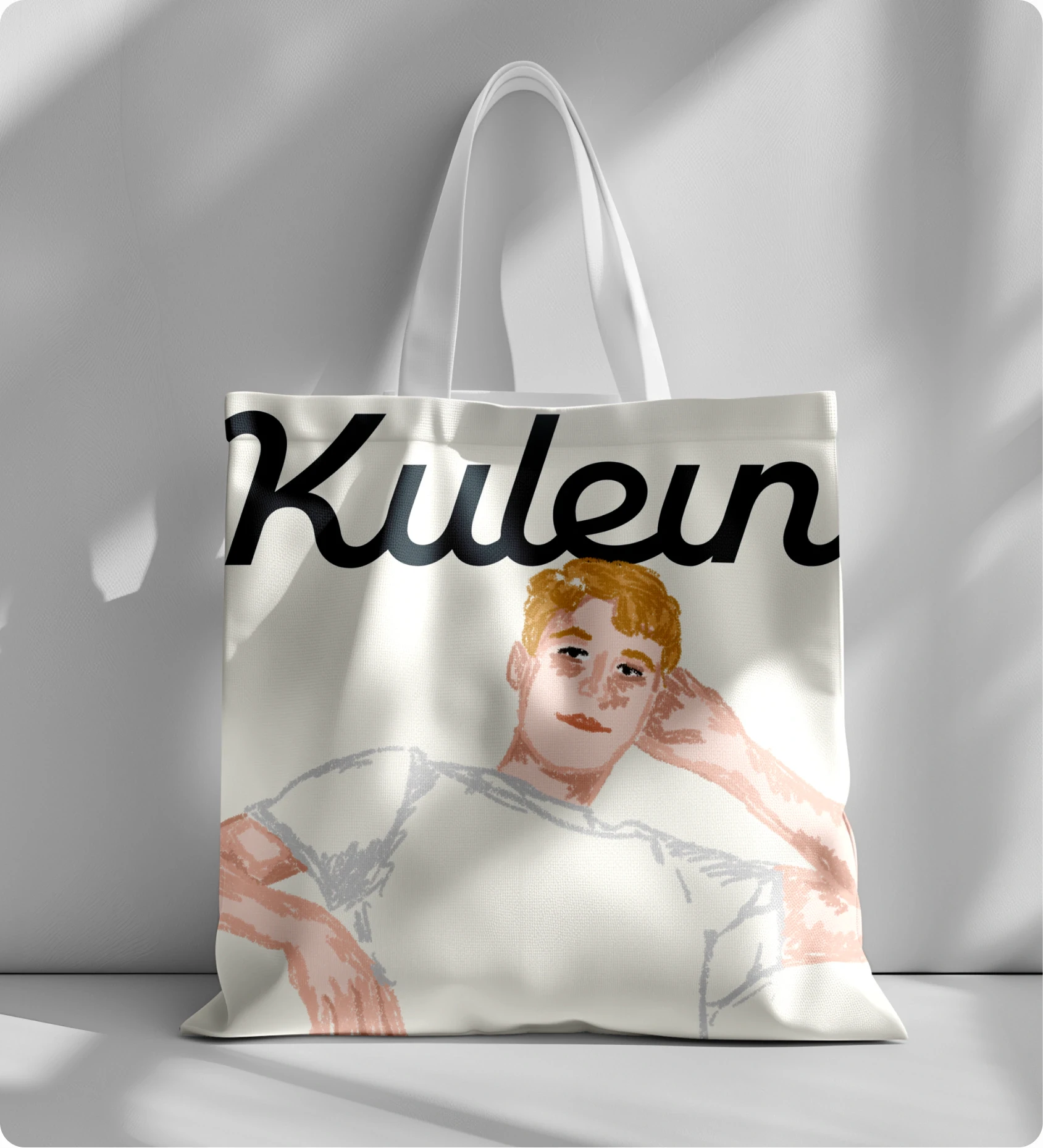 White tote bag with an illustration of a relaxed person with short orange hair and the word 'Kuleun' in bold black script above.